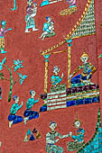 Wat Xieng Thong temple in Luang Prabang, Laos.  La Chapelle Rouge , the Red Chapel. The exterior walls are decorated with colourful mosaics on a pink background with scenes of people daily activities. West wall. 